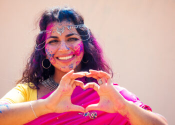 Holi Festival Of Colours. Portrait of happy indian girl in traditional hindu sari on holi color . india woman silver jewelry with powder paint on dress ,colourful pink and blue hair in Goa Kerala