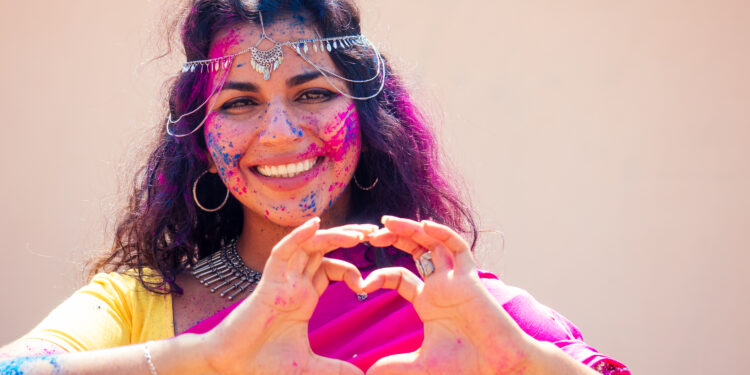 Holi Festival Of Colours. Portrait of happy indian girl in traditional hindu sari on holi color . india woman silver jewelry with powder paint on dress ,colourful pink and blue hair in Goa Kerala