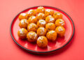 Boondi laddoos prasad decorated with silver leaf and pistachios, served on a red plate for Hanuman Jayanti