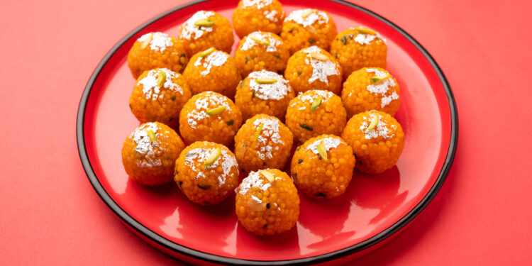 Boondi laddoos prasad decorated with silver leaf and pistachios, served on a red plate for Hanuman Jayanti