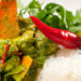 Close-up of Indo-Caribbean curry duck with white rice, red chilli, and coriander garnish