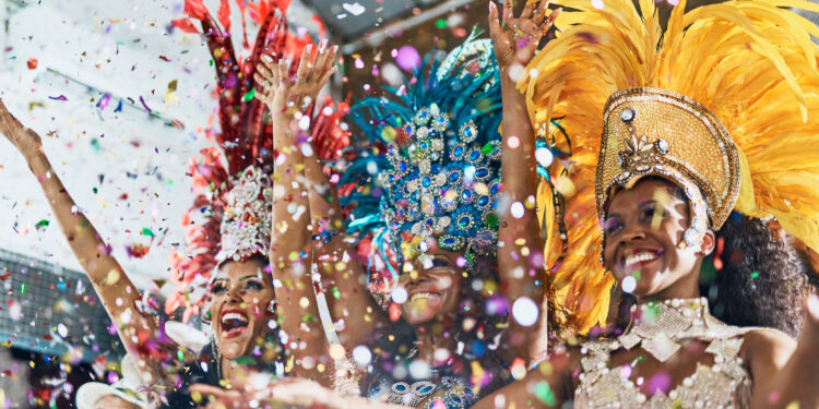 Samba dancers in colourful feathered costumes celebrating at Notting Hill Carnival 2025 with confetti in the air.