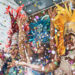 Samba dancers in colourful feathered costumes celebrating at Notting Hill Carnival 2025 with confetti in the air.