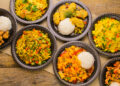 Assorted Indo-Caribbean fusion dishes served with rice on rustic wooden table