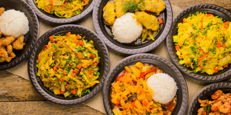 Assorted Indo-Caribbean fusion dishes served with rice on rustic wooden table