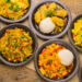 Assorted Indo-Caribbean fusion dishes served with rice on rustic wooden table