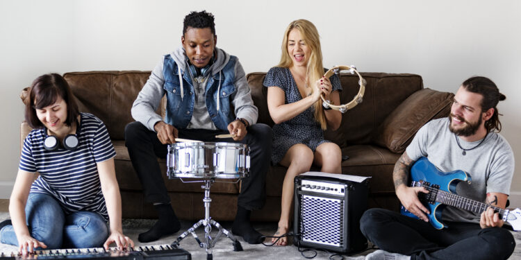 Musicians jamming with keyboard, drum, tambourine, and electric guitar in a cosy living room.
