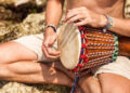 Indo-Caribbean devotees playing tassa and harmonium during a temple gathering, showing the role of music and drumming in spiritual healing and faith traditions.