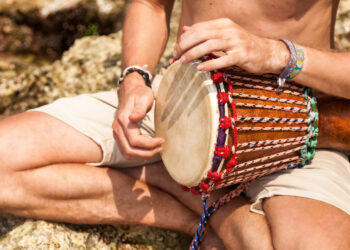 Indo-Caribbean devotees playing tassa and harmonium during a temple gathering, showing the role of music and drumming in spiritual healing and faith traditions.