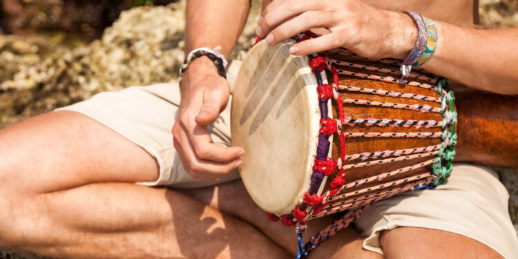 Indo-Caribbean devotees playing tassa and harmonium during a temple gathering, showing the role of music and drumming in spiritual healing and faith traditions.