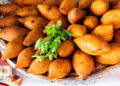 Golden fried Trini pholourie and Guyanese pholourie balls served with tamarind and mango chutneys on a rustic plate.