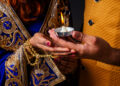Close-up of a couple holding a lit diya during Karva Chauth celebrations, symbolising love, devotion, and tradition.