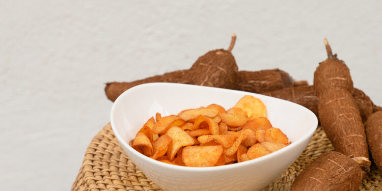 A colourful spread of Caribbean comfort foods featuring sweet potato fries, cassava pone, and bammy bread served alongside curry and fried fish in a UK kitchen setting.