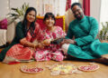 A UK Indo-Caribbean family cooking together in a warm kitchen, passing down traditional recipes like roti and dhal while children watch and help.