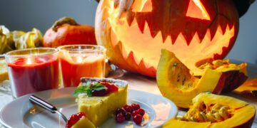 A festive Indo-Caribbean Halloween table with pumpkin curry, candles, and Caribbean-Indian decorations.