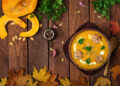 A vibrant Indo-Caribbean pumpkin curry simmering in a cast-iron pot, surrounded by fresh herbs, spices, and golden autumn leaves — celebrating seasonal cooking with Caribbean warmth.