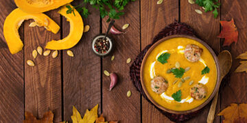 A vibrant Indo-Caribbean pumpkin curry simmering in a cast-iron pot, surrounded by fresh herbs, spices, and golden autumn leaves — celebrating seasonal cooking with Caribbean warmth.