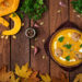A vibrant Indo-Caribbean pumpkin curry simmering in a cast-iron pot, surrounded by fresh herbs, spices, and golden autumn leaves — celebrating seasonal cooking with Caribbean warmth.