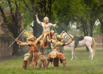 An elder sharing Indo-Caribbean folktales under warm evening light, surrounded by family, symbolising the fusion of Anansi stories and Indian epics in Caribbean culture.