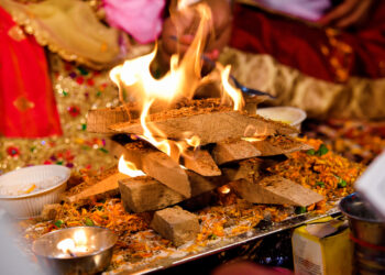 Lohri bonfire celebration with families gathered around the fire, sharing traditional foods like til laddoos, gajak, peanuts, and popcorn during the winter festival.
