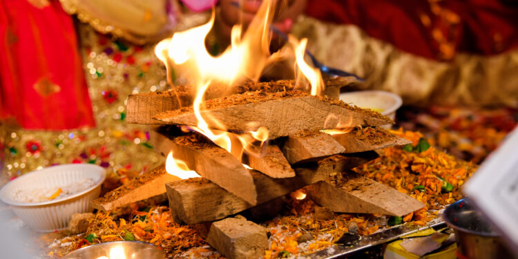 Lohri bonfire celebration with families gathered around the fire, sharing traditional foods like til laddoos, gajak, peanuts, and popcorn during the winter festival.