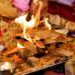 Lohri bonfire celebration with families gathered around the fire, sharing traditional foods like til laddoos, gajak, peanuts, and popcorn during the winter festival.