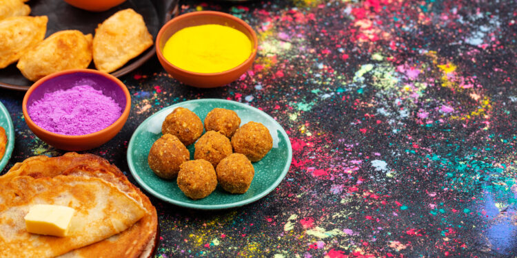 A cosy Lohri party celebration in the UK with family and friends gathered around a small fire pit, wearing colourful Punjabi attire and enjoying traditional food.