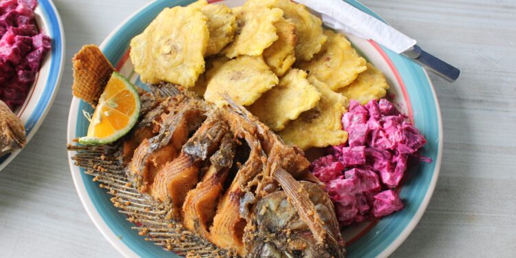 Plate of fried fish served with tostones and beetroot salad in a Caribbean-style meal
