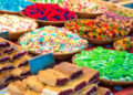 Colourful baskets of assorted festival sweets and pastries displayed at a vibrant market stall, including gummy candies, sugar-coated treats, and fruit-filled pastries reminiscent of Caribbean Carnival sweet snacks.