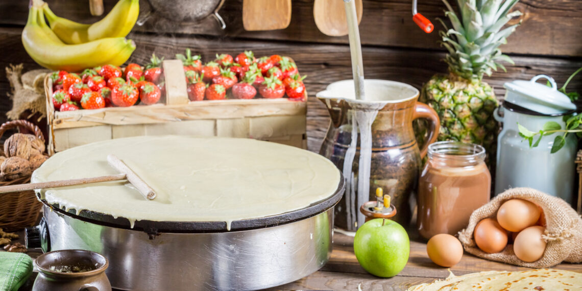 Various roti-making equipment including a tawa pan, cast iron griddle, belna rolling pin, and roti press arranged on a kitchen countertop, ready for preparing fresh rotis at home.