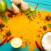 Colourful Caribbean spice spread with turmeric powder, ginger, garlic, lime, chillies, star anise, mint, and coconut on a blue wooden surface
