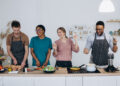 Woman in a modern UK kitchen preparing to clean while surrounded by household items, reflecting the busy reality behind global home cooking trends in 2026.