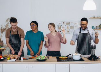Woman in a modern UK kitchen preparing to clean while surrounded by household items, reflecting the busy reality behind global home cooking trends in 2026.