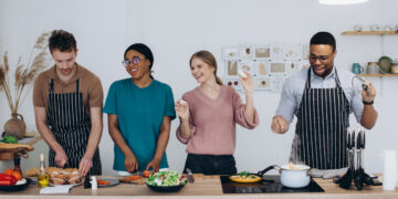 Woman in a modern UK kitchen preparing to clean while surrounded by household items, reflecting the busy reality behind global home cooking trends in 2026.