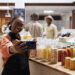 Bustling UK food market stall serving Caribbean, African and Asian street food with colourful dishes, spices, and customers enjoying global flavours.