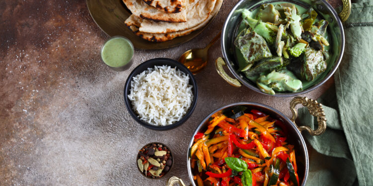 Colourful vegetarian meal with rice, naan bread, and vegetable curry dishes representing bold flavours in vegetarian cooking around the world.