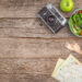 Travel-friendly healthy meal setup on a rustic wooden table with fresh salad bowls, tea, a vintage camera, reusable flask, and map for outdoor adventure inspiration.